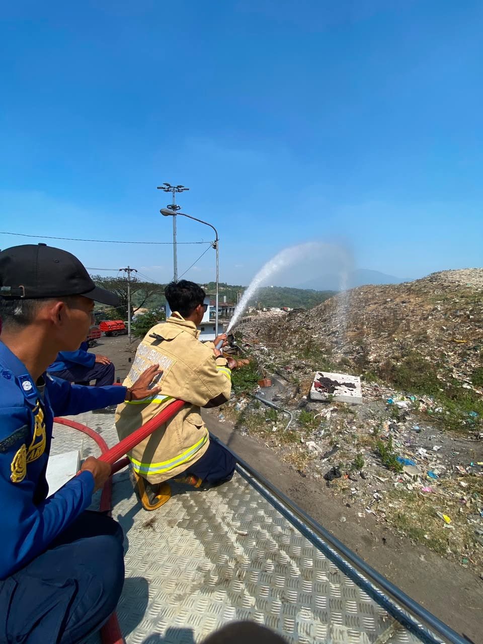Petugas gabungan DLH dan Damkar Semarang semprotkan air ke area rawan kebakaran TPA Jatibarang.